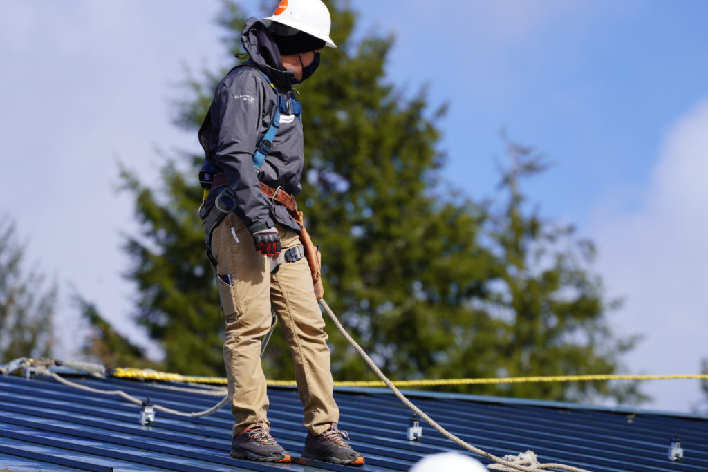 Photo of worker on a roof installing solar panels at Quinault Indian Nation
